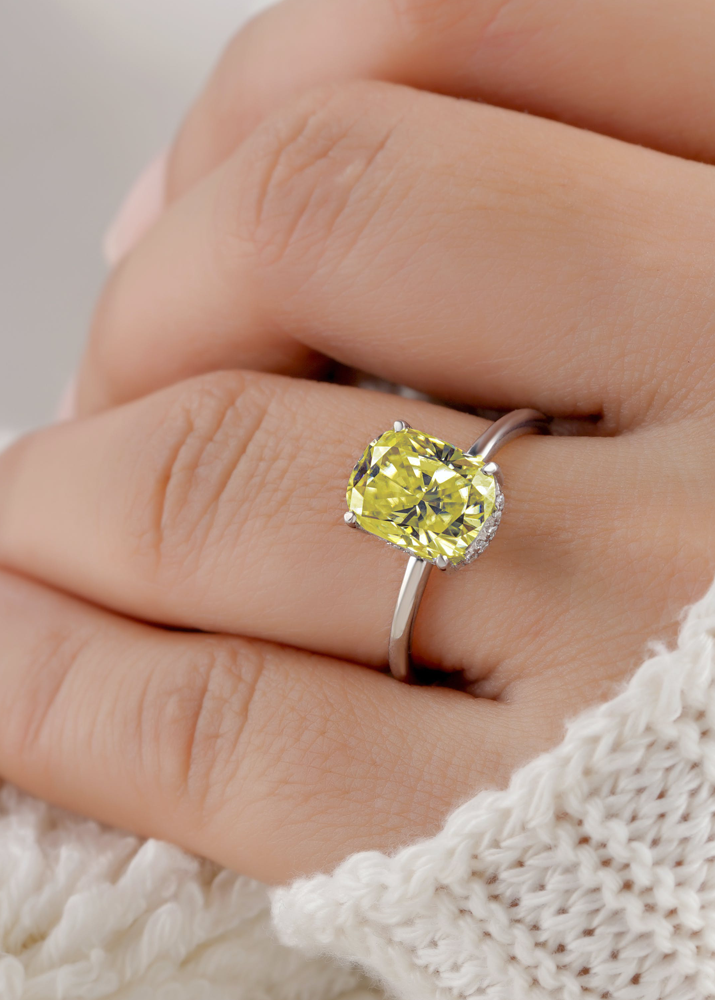 Close view of a yellow cushion cut stone in four claws above a slim polished white metal band