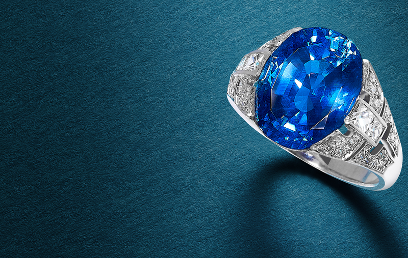 White metal ring with a large oval blue stone and clear stone set shoulders, on a teal background