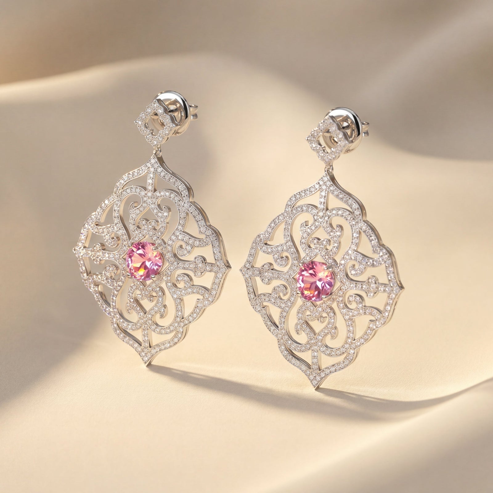 Ornate earrings with pink gemstones on a beige fabric background