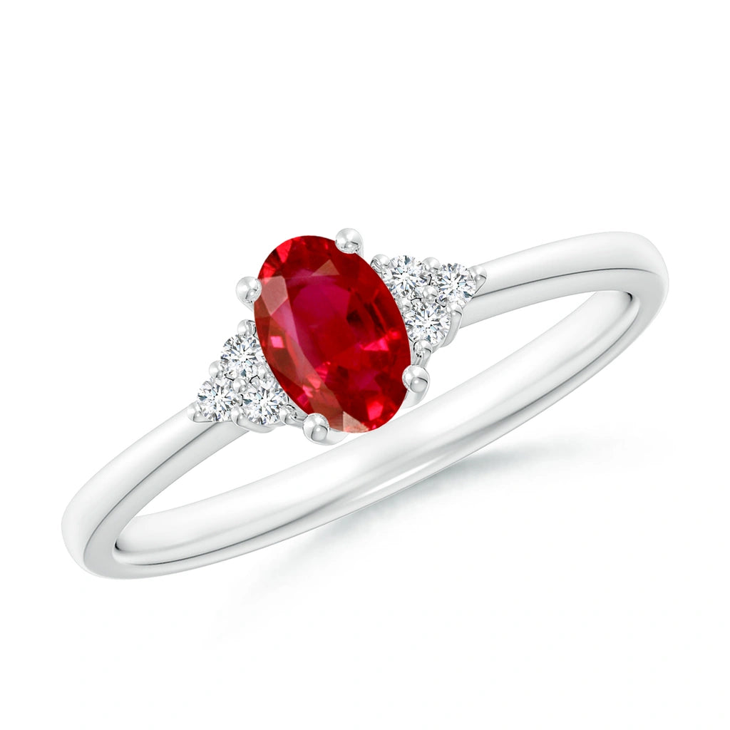 Upright oval ruby in white metal with a trio of small diamonds on each shoulder and a plain band