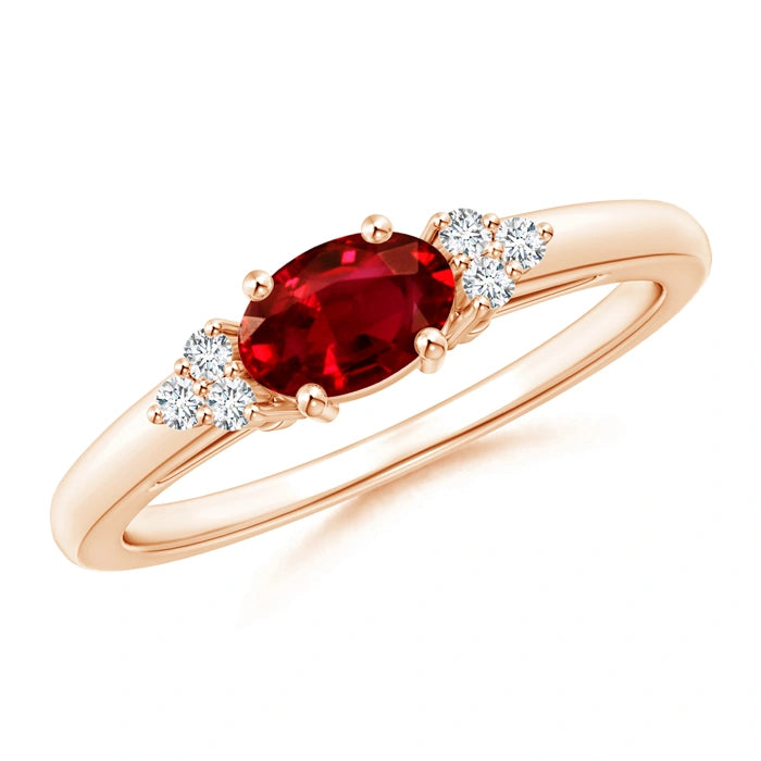 Rose gold ring with an oval ruby set across the band and three small diamonds to each side